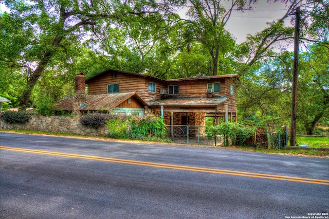 view of front of property with a gate, stone siding, a chimney, and fence