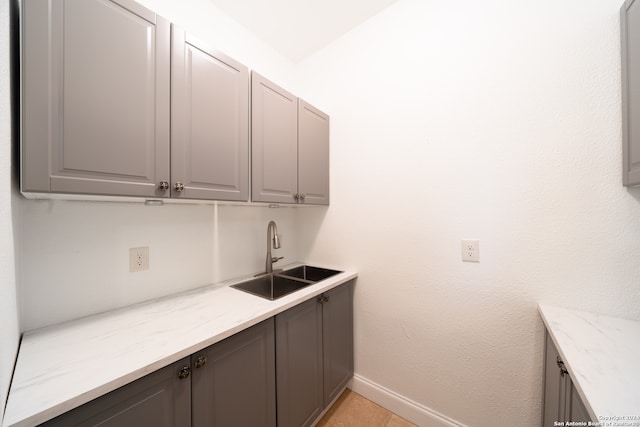 clothes washing area featuring light tile patterned floors and sink