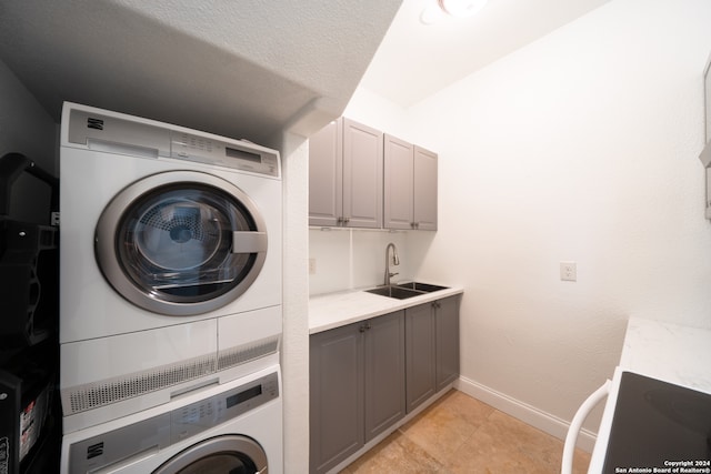 laundry area featuring cabinets, sink, and stacked washer and dryer