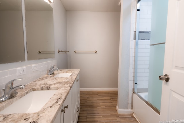 bathroom with vanity, bath / shower combo with glass door, wood-type flooring, and decorative backsplash