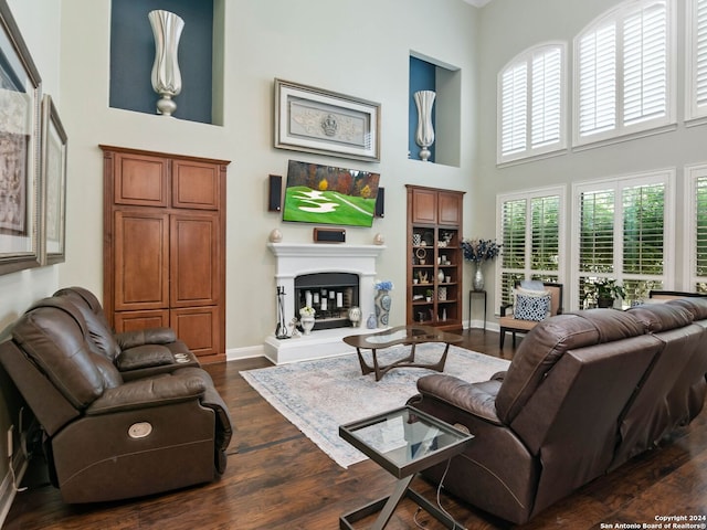 living room with dark hardwood / wood-style flooring and a towering ceiling