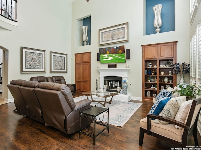 living room featuring a towering ceiling and dark wood-type flooring