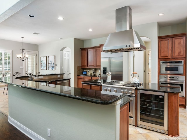 kitchen featuring high end appliances, a chandelier, island range hood, beverage cooler, and a center island