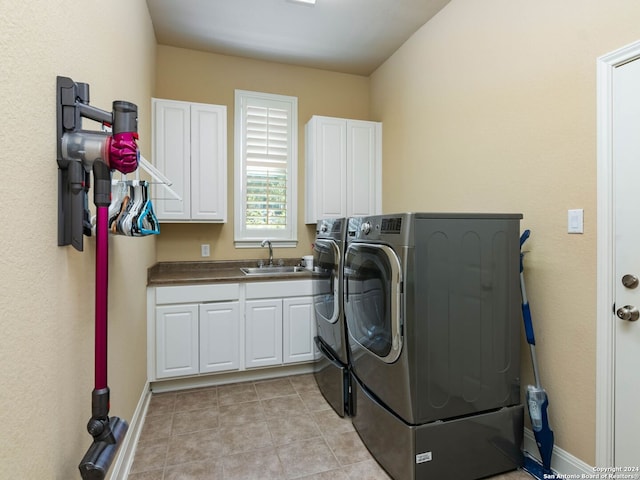 laundry room with light tile patterned floors, cabinets, washing machine and clothes dryer, and sink