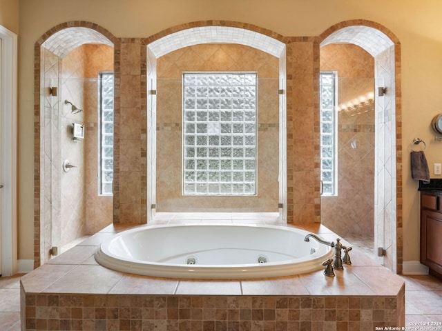 bathroom with tiled tub, vanity, plenty of natural light, and tile patterned flooring