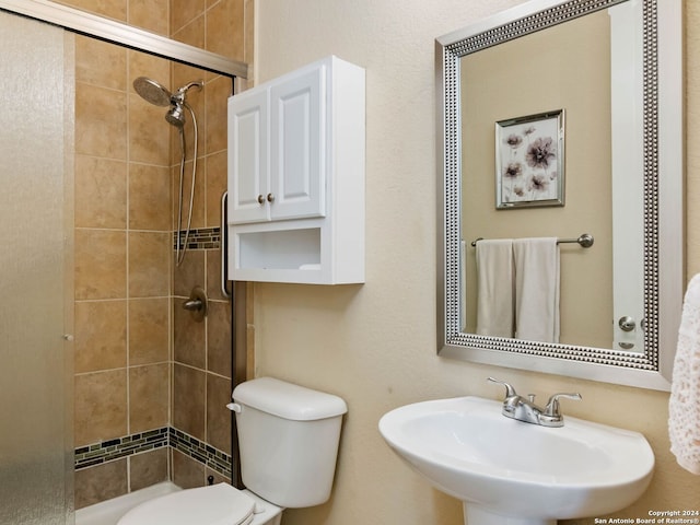 bathroom featuring toilet, sink, and a shower with door