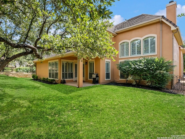 back of property with a yard and a patio area