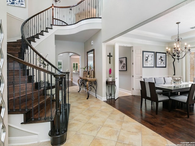 entryway featuring ornamental molding, wood-type flooring, a tray ceiling, and a notable chandelier