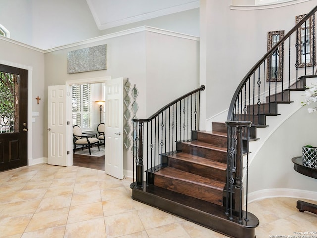 entryway with crown molding, a high ceiling, and light hardwood / wood-style floors