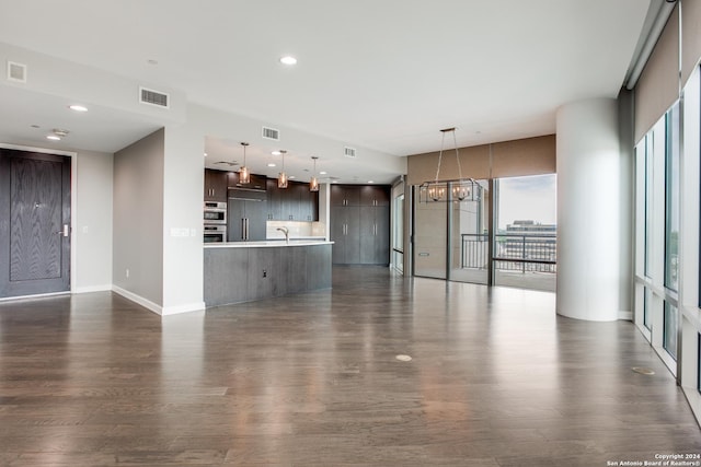 unfurnished living room featuring dark wood-style flooring, visible vents, and baseboards