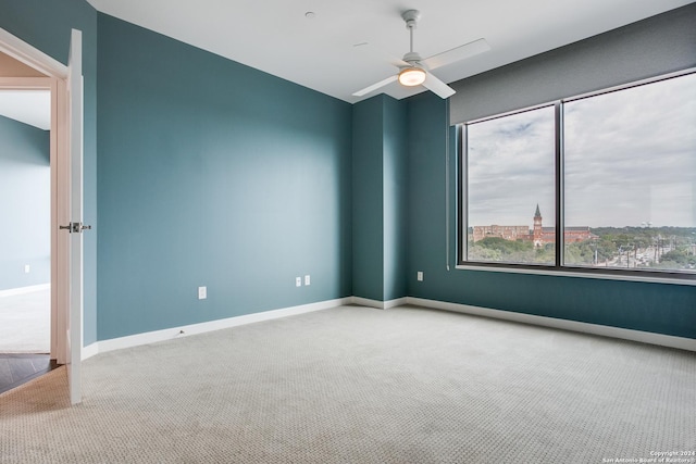 carpeted spare room with ceiling fan and baseboards