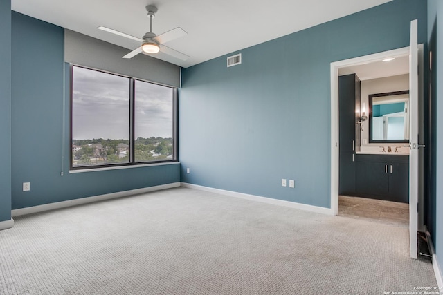 carpeted spare room with a sink, baseboards, visible vents, and a ceiling fan