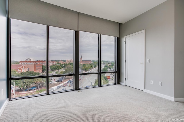 spare room featuring carpet, baseboards, and a view of city