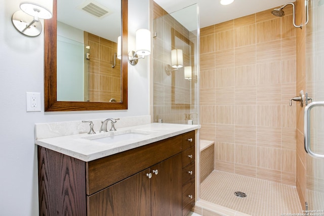 full bathroom featuring visible vents, tiled shower, and vanity