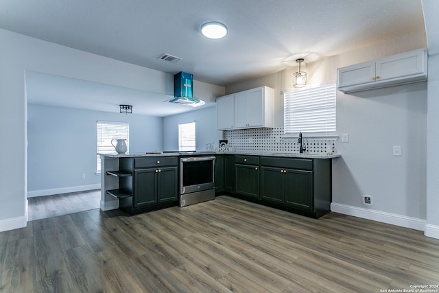 kitchen featuring white cabinets, hardwood / wood-style flooring, stainless steel stove, island exhaust hood, and kitchen peninsula