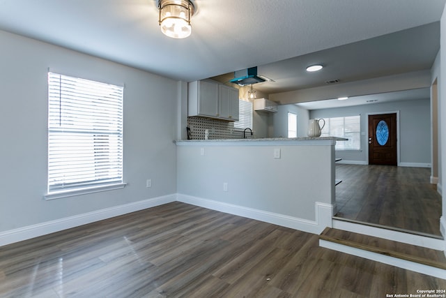 kitchen with a breakfast bar area, wood-type flooring, kitchen peninsula, and backsplash