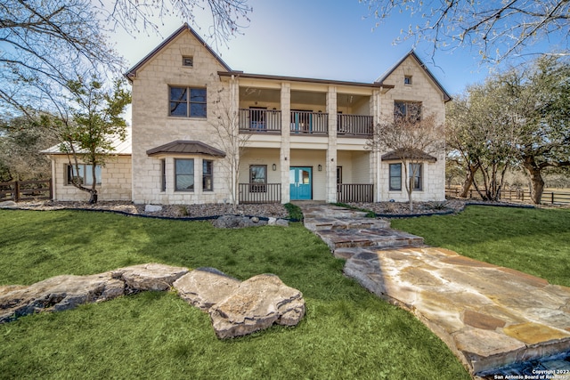 view of front of house featuring a balcony and a front yard