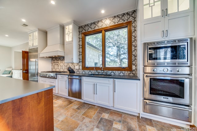 kitchen featuring built in appliances, custom exhaust hood, white cabinets, and sink