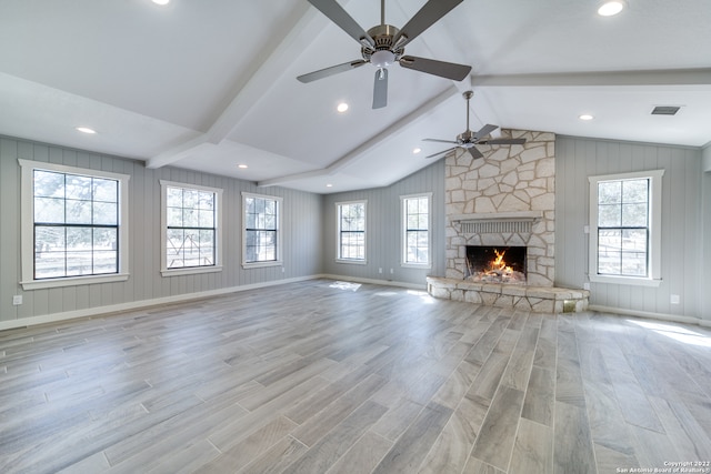 unfurnished living room with plenty of natural light, a stone fireplace, and light hardwood / wood-style flooring