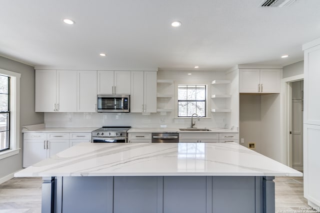 kitchen featuring white cabinetry, a healthy amount of sunlight, light stone counters, and stainless steel appliances