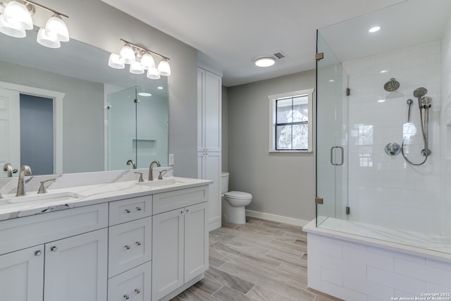 bathroom with hardwood / wood-style floors, toilet, a shower with door, and vanity