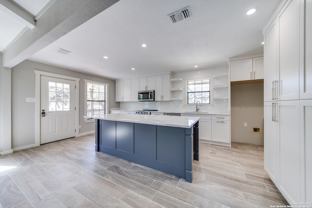 kitchen featuring white cabinetry, light hardwood / wood-style flooring, stainless steel appliances, a kitchen island, and sink