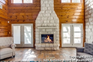 living room featuring high vaulted ceiling and a stone fireplace