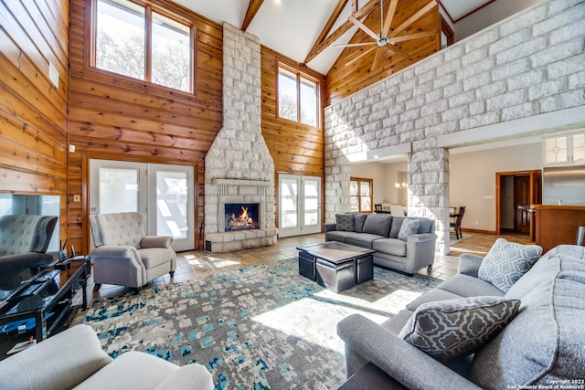 living room featuring high vaulted ceiling, ceiling fan, a healthy amount of sunlight, and a stone fireplace