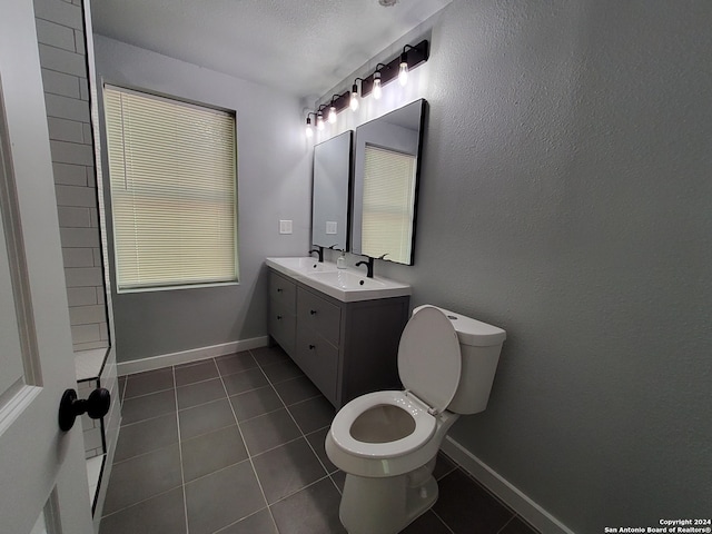 bathroom with vanity, toilet, a textured ceiling, and tile patterned flooring