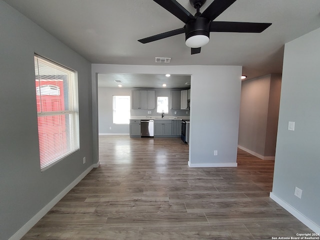 unfurnished living room with hardwood / wood-style floors, sink, and ceiling fan