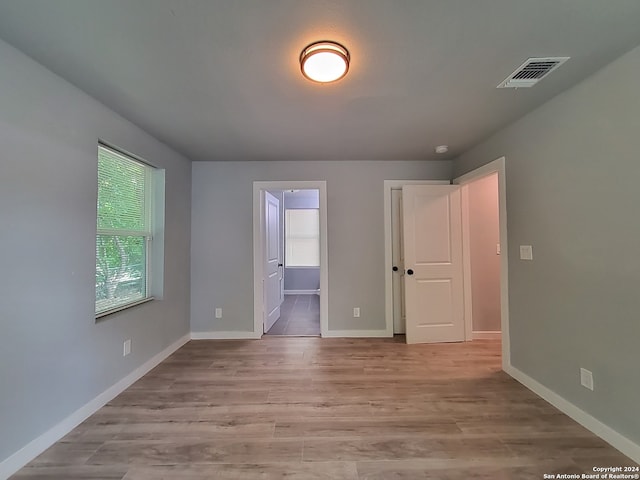 unfurnished bedroom with ensuite bath and light hardwood / wood-style flooring