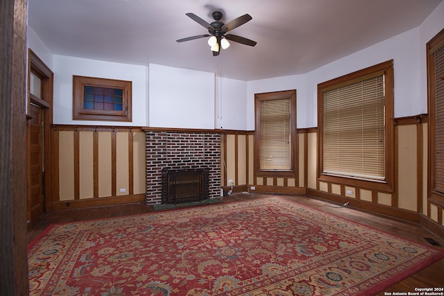 living room featuring ceiling fan, dark hardwood / wood-style floors, and a brick fireplace