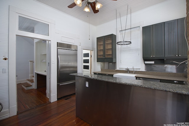 kitchen featuring stainless steel built in refrigerator, dark hardwood / wood-style flooring, dark stone counters, and ceiling fan