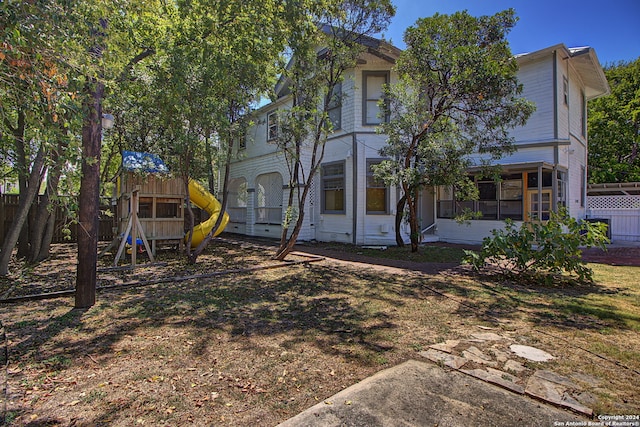 rear view of property with a playground