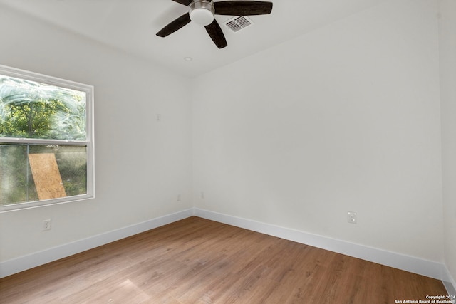 empty room featuring a healthy amount of sunlight, ceiling fan, and hardwood / wood-style floors