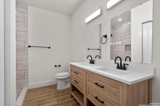 bathroom featuring vanity, toilet, hardwood / wood-style floors, and a tile shower