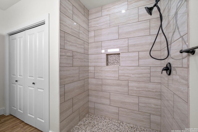 bathroom with tiled shower and wood-type flooring