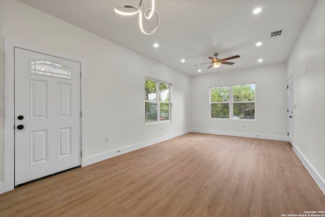 foyer entrance with plenty of natural light, light hardwood / wood-style flooring, and ceiling fan with notable chandelier