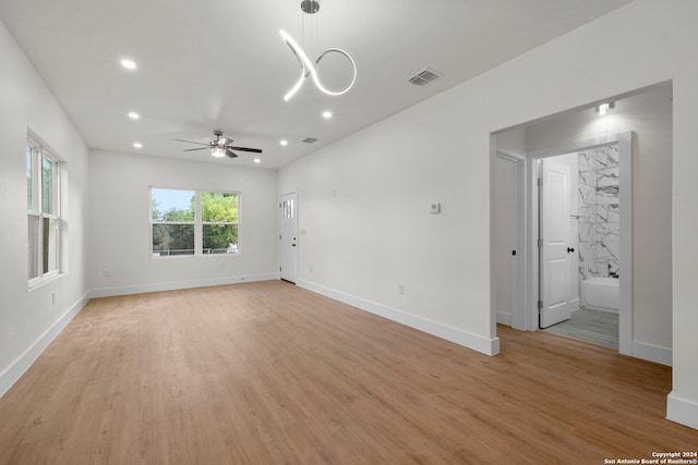 interior space featuring ceiling fan with notable chandelier and light hardwood / wood-style floors