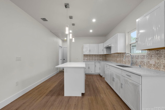 kitchen with a kitchen island, hardwood / wood-style floors, sink, decorative backsplash, and white cabinets