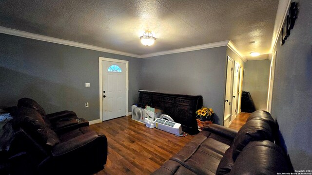 living room with wood-type flooring, a textured ceiling, and ornamental molding