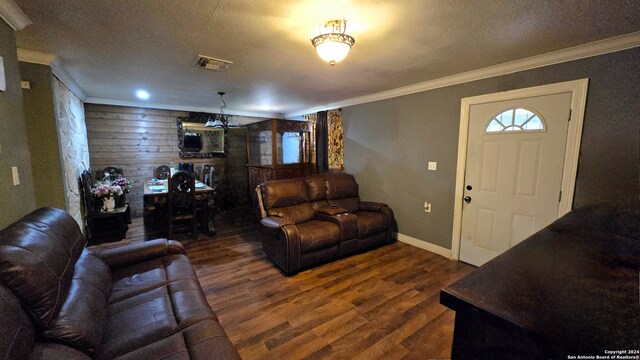 living room with dark hardwood / wood-style floors, a textured ceiling, a notable chandelier, and ornamental molding