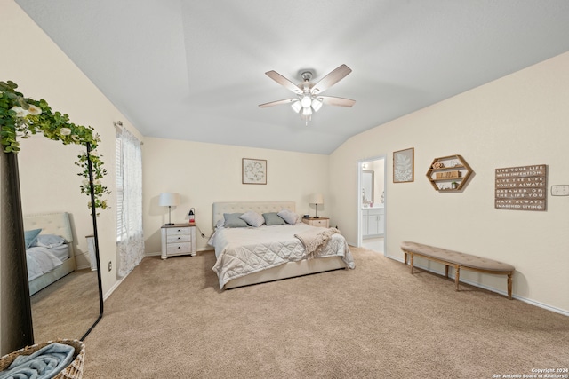 bedroom featuring ensuite bath, light carpet, vaulted ceiling, and ceiling fan