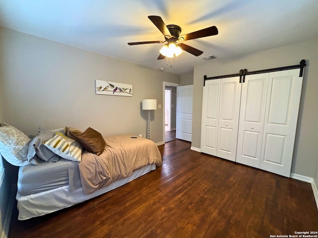 bedroom featuring ceiling fan, a barn door, and dark hardwood / wood-style floors