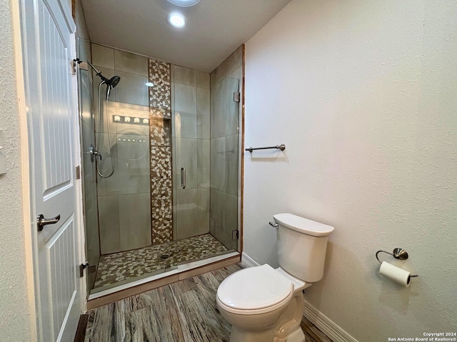 bathroom with wood-type flooring, toilet, and a shower with shower door