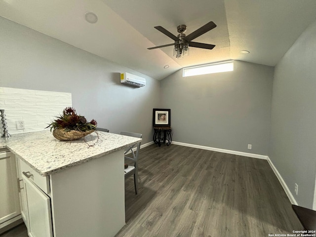 kitchen featuring vaulted ceiling, dark wood-type flooring, an AC wall unit, ceiling fan, and light stone counters