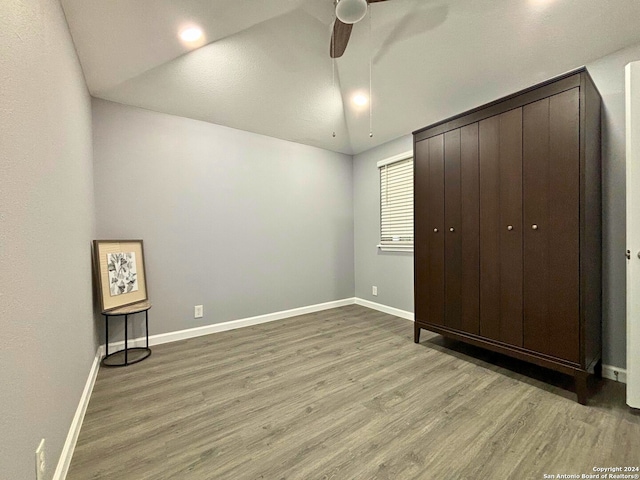 unfurnished bedroom featuring lofted ceiling, wood-type flooring, ceiling fan, and a closet