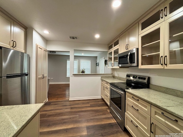 kitchen with light stone countertops, stainless steel appliances, and dark hardwood / wood-style flooring