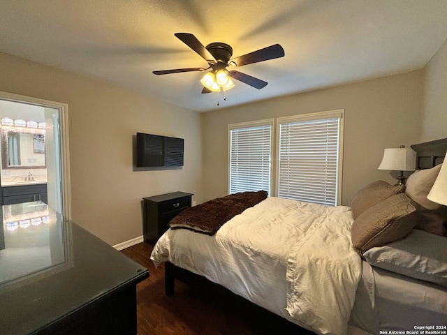 bedroom with multiple windows, dark hardwood / wood-style flooring, ceiling fan, and connected bathroom