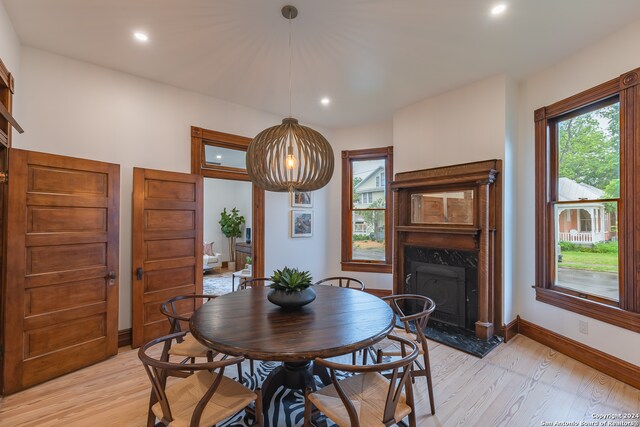 dining space featuring light wood-type flooring and a premium fireplace